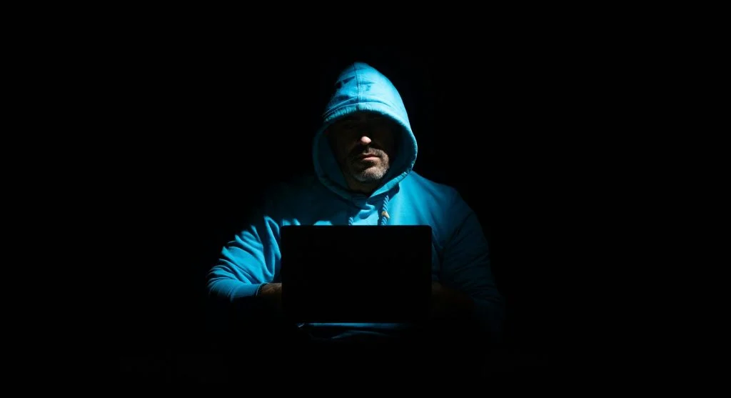 Illustration of a person using a laptop in a public place with a warning symbol
