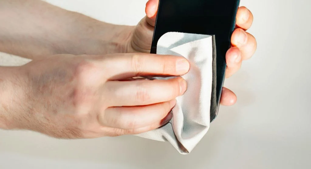 Person gently wiping smartphone screen with a soft cloth