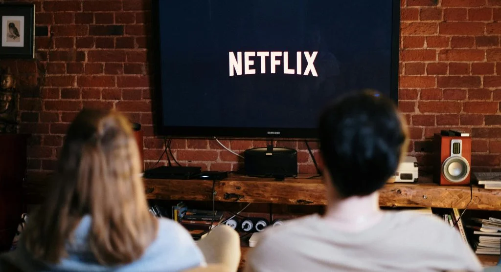 Person holding remote control in front of a large screen smart TV
