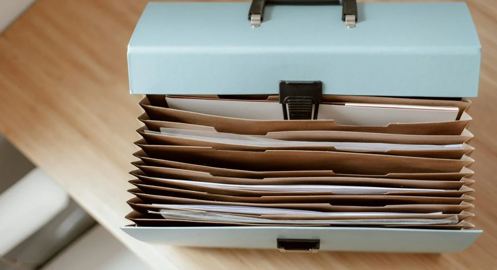 A person organizing files into color-coded folders on a desk