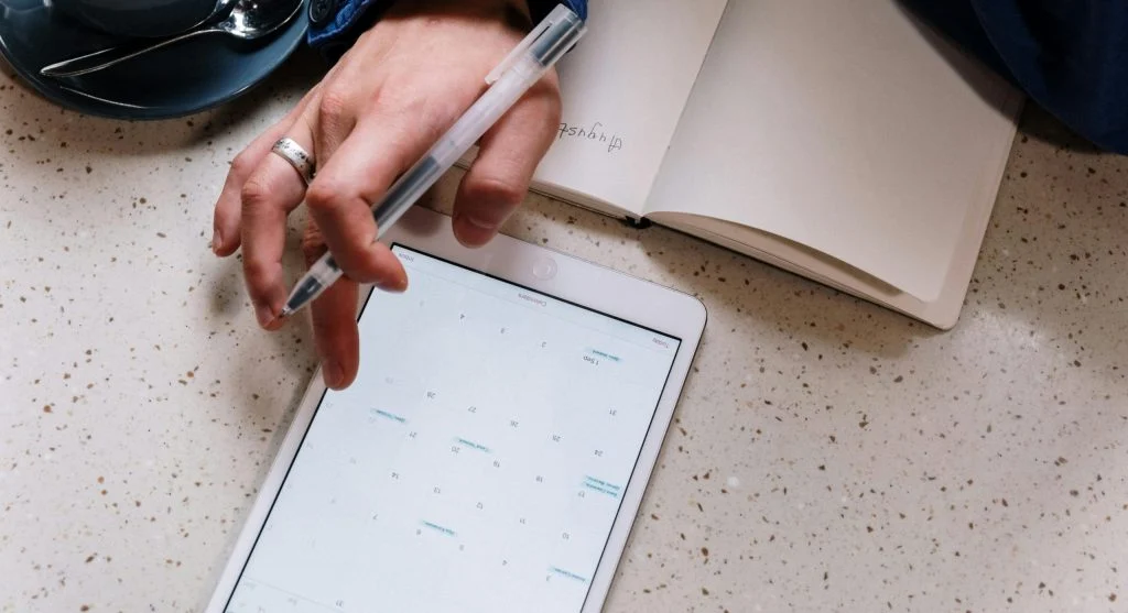 Person holding a tablet with a planner app on the screen
